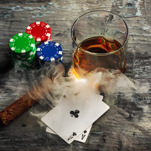 Cigar, chips for gamblings, drink and playing cards on wooden table. Poker concept